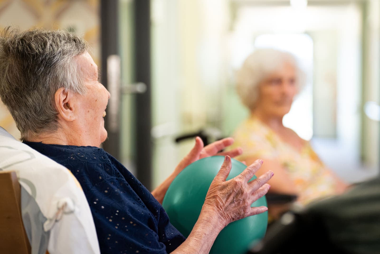 Seniorin und Pflegekraft bei der Gymnastik mit Ball