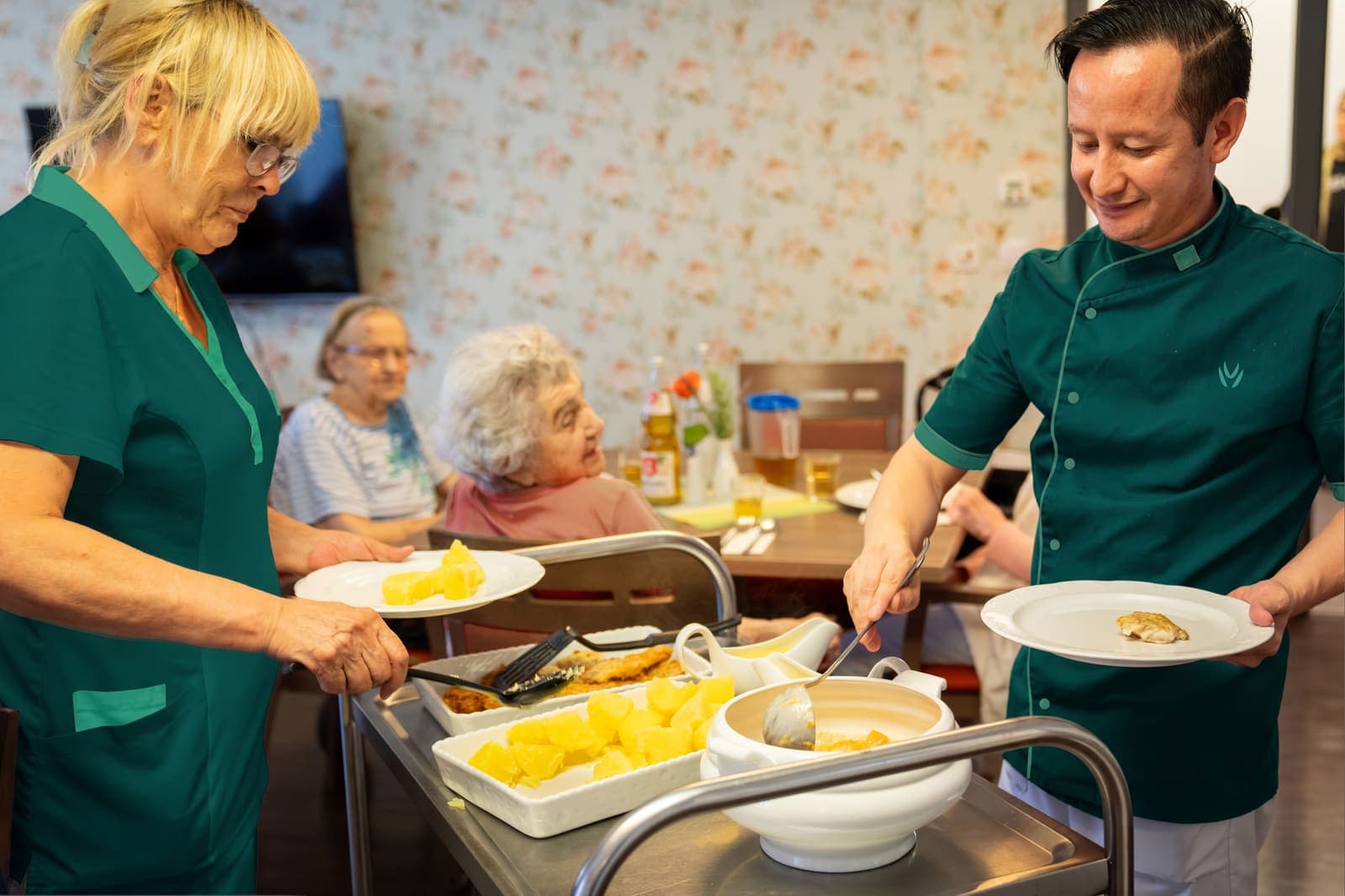 Pflegekräfte servieren Senioren das Mittagessen