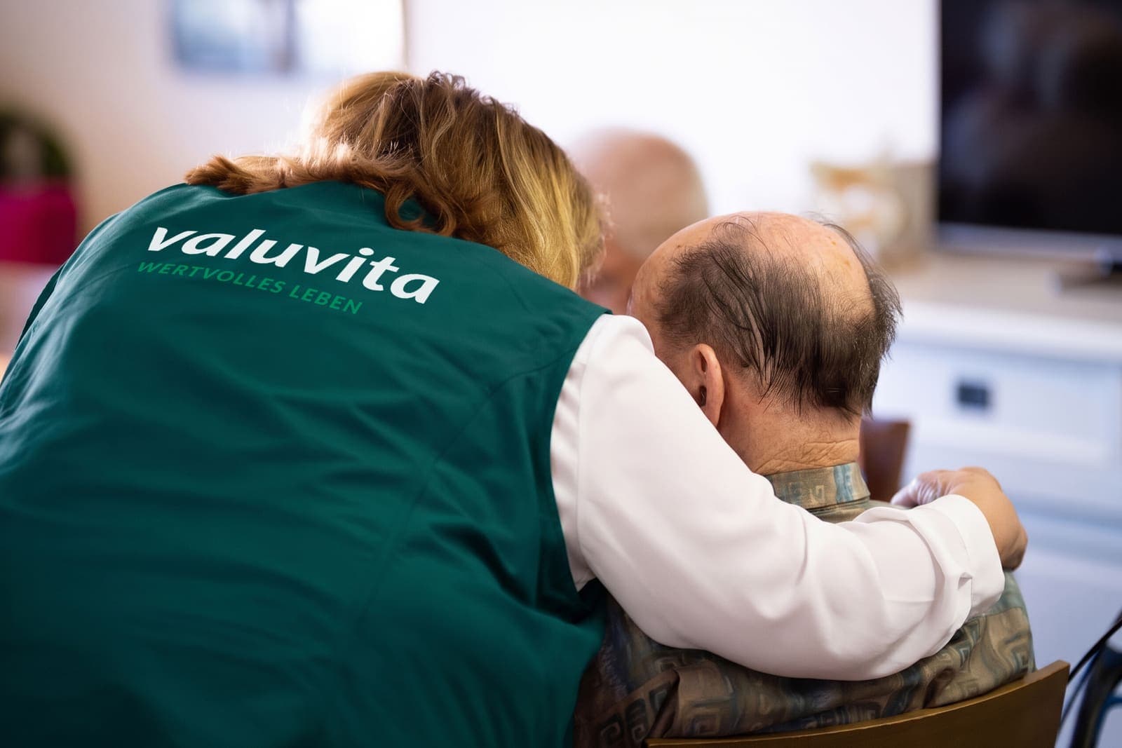 Pflegekraft legt einem Senior den Arm um die Schulter